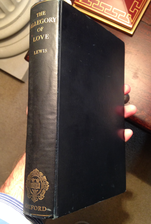 A hardback black book with the title "Allegory of Love" and the author name "Lewis" written on the spine in gold letters.